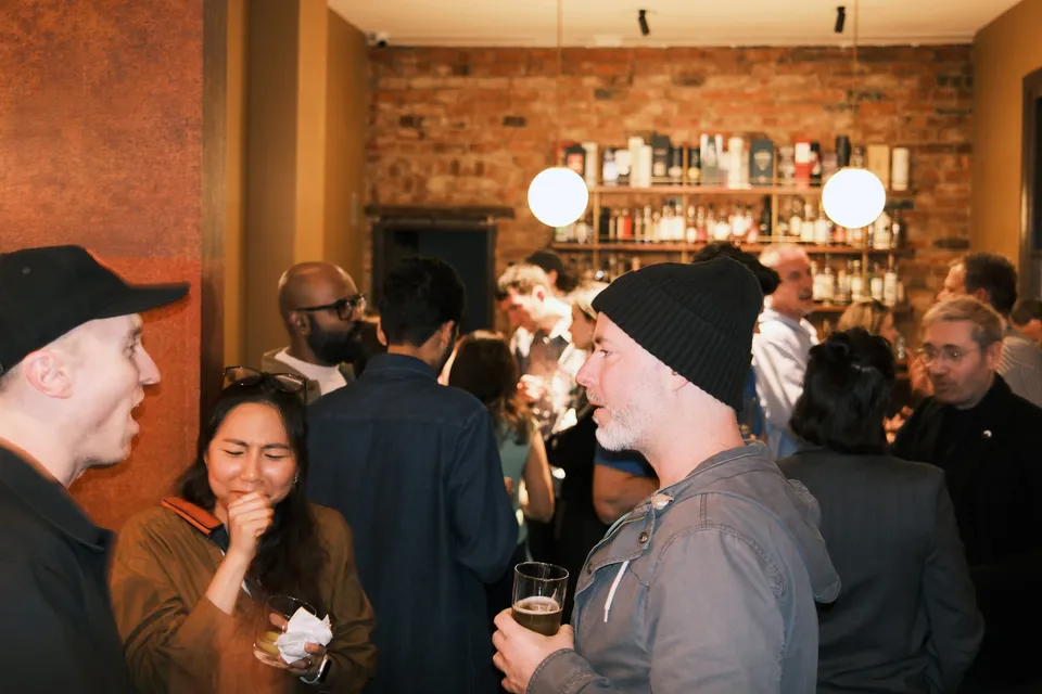 Guests mingling in the warmly lit bar at AI Ops 008